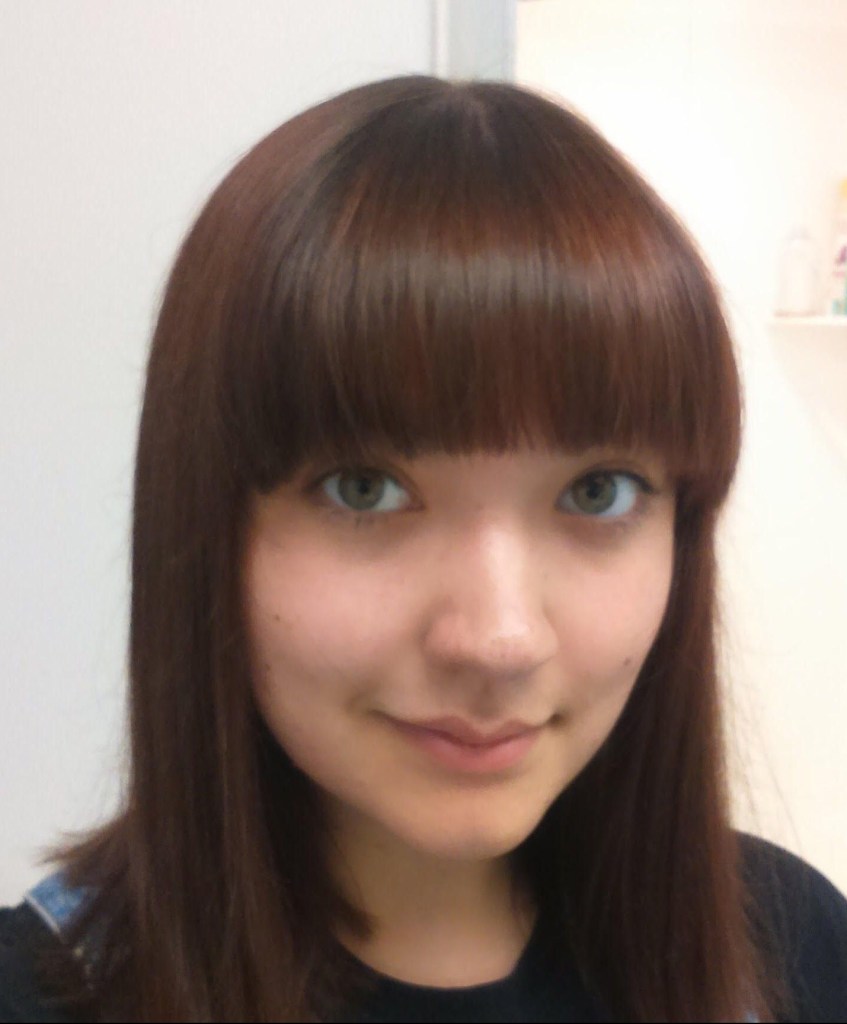 Slightly smiling woman with shoulder-length auburn hair and bangs or fringe.